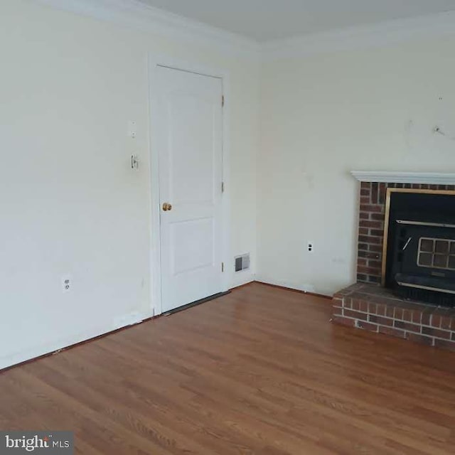 unfurnished living room with crown molding, wood-type flooring, and a brick fireplace