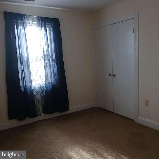 unfurnished bedroom with a closet and carpet flooring