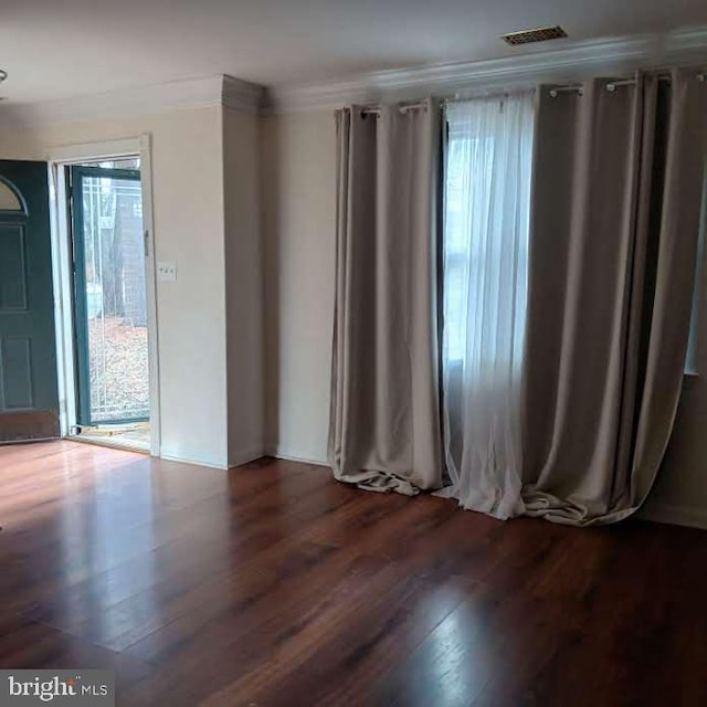 empty room featuring dark wood-type flooring and ornamental molding