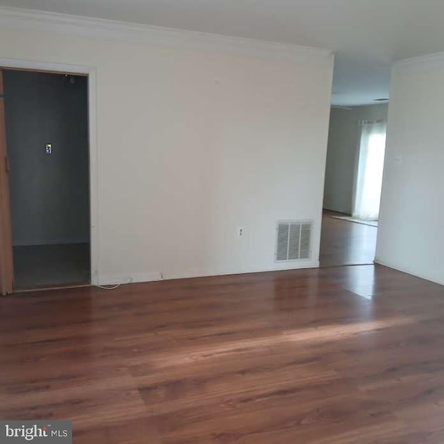 unfurnished room featuring dark wood-type flooring and ornamental molding