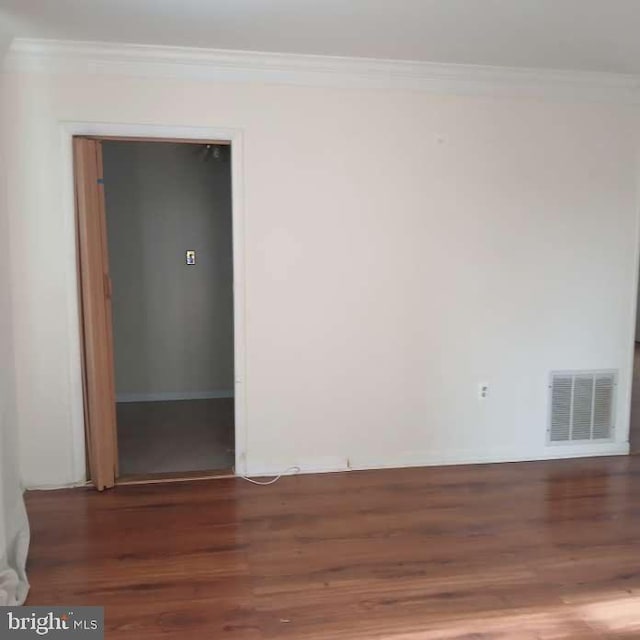 empty room featuring dark wood-type flooring and ornamental molding