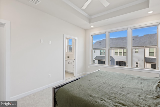 carpeted bedroom with ceiling fan, ensuite bath, crown molding, and a raised ceiling