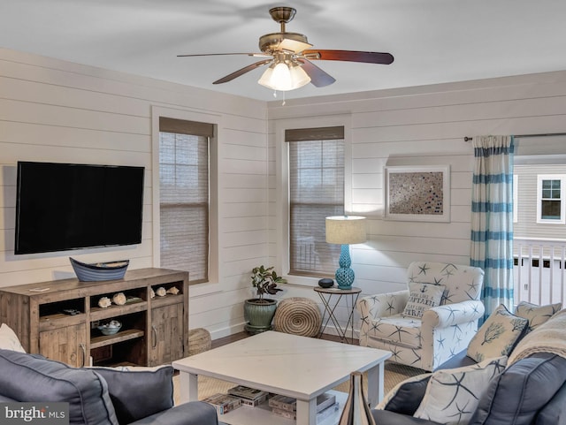 living room featuring wooden walls and ceiling fan