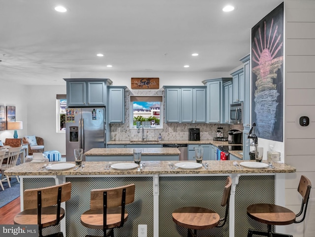 kitchen featuring stainless steel appliances, sink, a kitchen breakfast bar, and kitchen peninsula