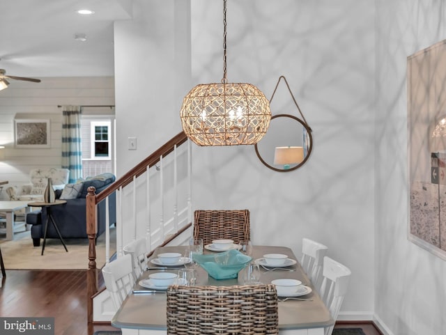 dining room with ceiling fan with notable chandelier and dark hardwood / wood-style flooring