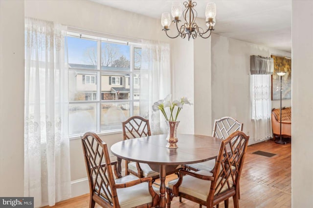 dining space featuring a wealth of natural light, an inviting chandelier, and light hardwood / wood-style flooring