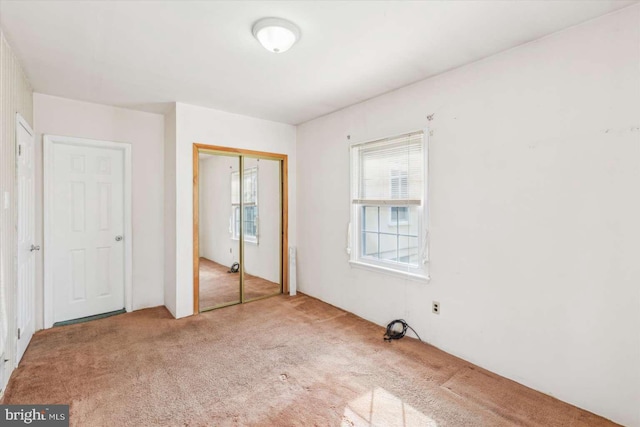 unfurnished bedroom with light carpet and a closet