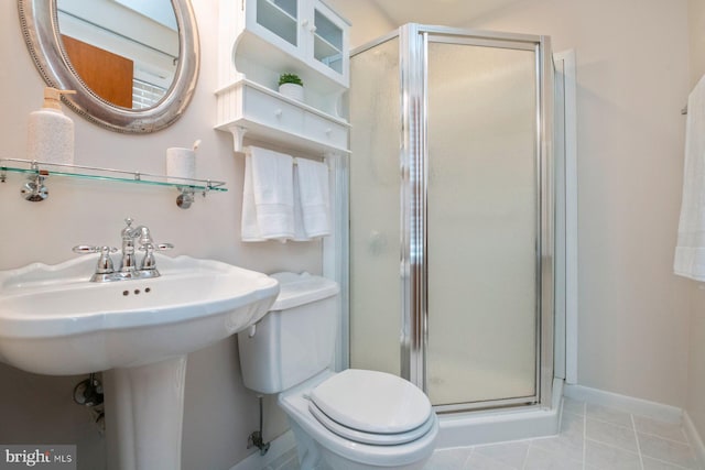 bathroom with toilet, tile patterned floors, and a shower with shower door