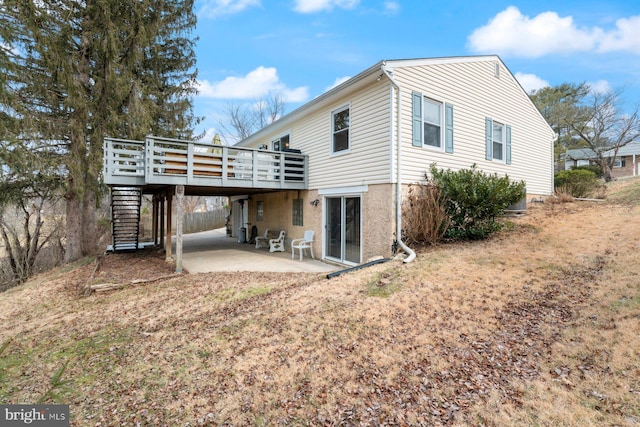 rear view of house featuring a wooden deck and a patio