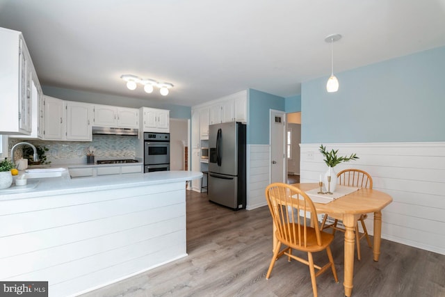 kitchen with pendant lighting, sink, white cabinets, kitchen peninsula, and stainless steel appliances