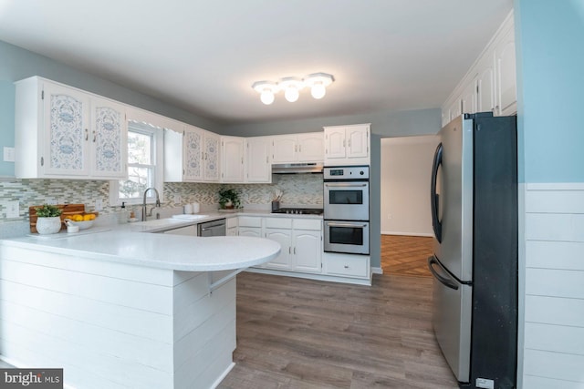 kitchen featuring hardwood / wood-style flooring, appliances with stainless steel finishes, kitchen peninsula, and white cabinets