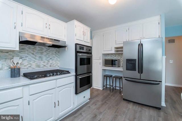 kitchen featuring tasteful backsplash, hardwood / wood-style flooring, white cabinets, and appliances with stainless steel finishes