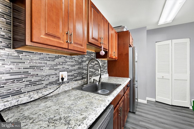 kitchen with sink, stainless steel fridge, dark wood-type flooring, tasteful backsplash, and light stone counters