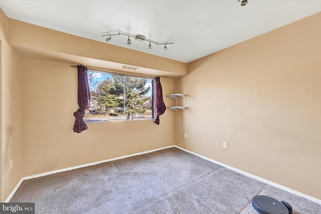 carpeted empty room with rail lighting