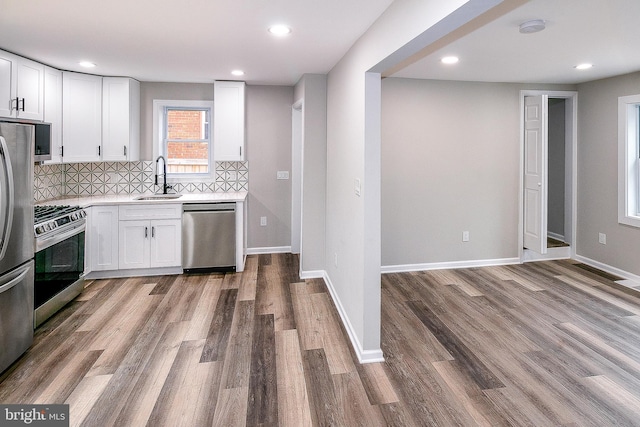 5006 Edgewood Rd, College Park, MD 20740 - kitchen with sink, wood-type flooring, stainless steel appliances, decorative backsplash, and white cabinets