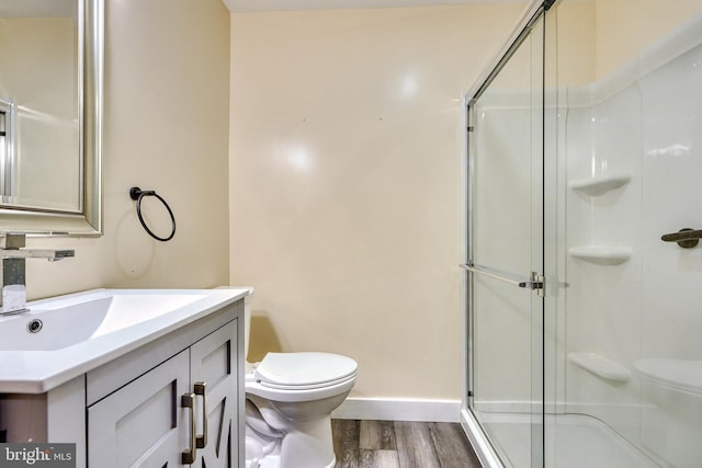 bathroom with vanity, hardwood / wood-style floors, a shower with door, and toilet