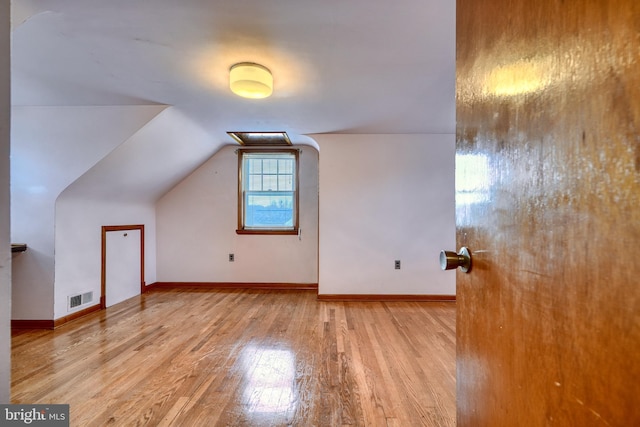 additional living space featuring vaulted ceiling and light hardwood / wood-style flooring