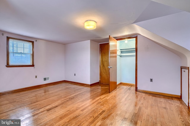 additional living space featuring lofted ceiling and light hardwood / wood-style flooring