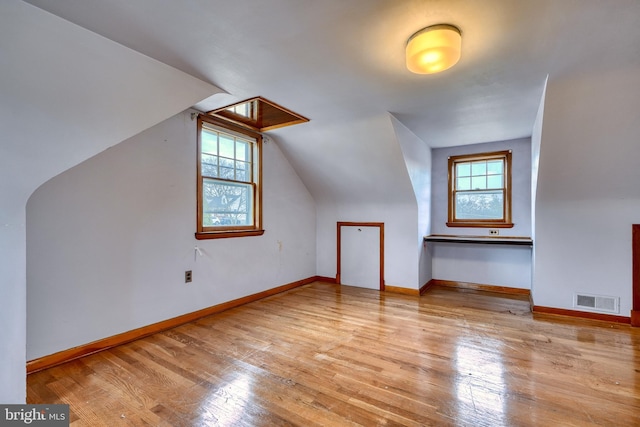 additional living space featuring vaulted ceiling, plenty of natural light, and light hardwood / wood-style floors