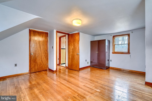 additional living space with light hardwood / wood-style flooring and vaulted ceiling