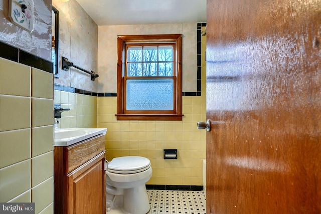 bathroom featuring vanity, tile walls, and toilet