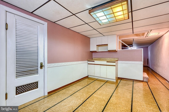 kitchen with a paneled ceiling and white cabinets