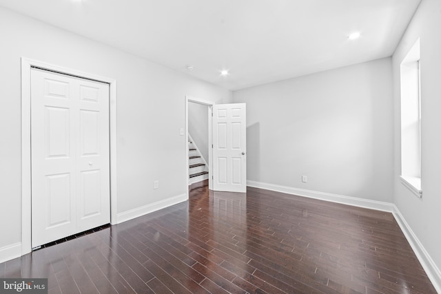 unfurnished bedroom featuring a closet and dark hardwood / wood-style floors