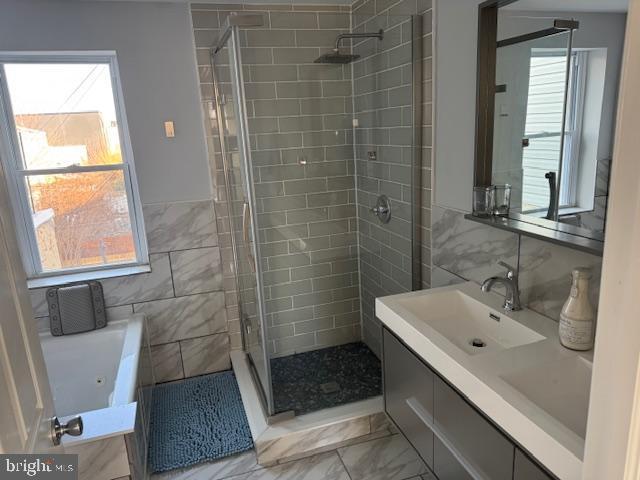 bathroom with vanity, separate shower and tub, and tile walls