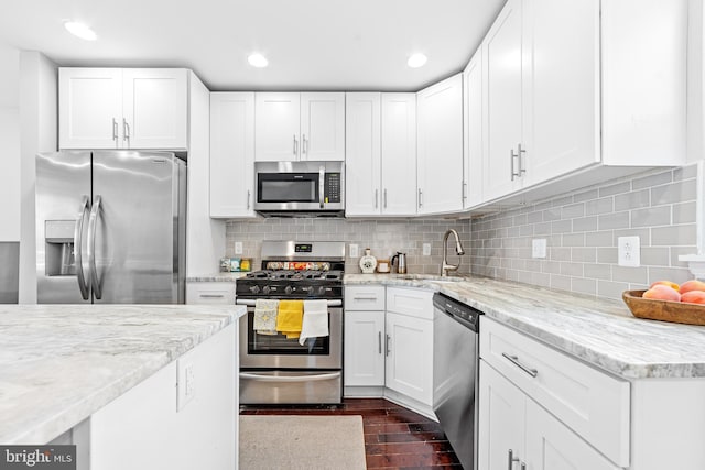 kitchen with sink, light stone counters, stainless steel appliances, decorative backsplash, and white cabinets