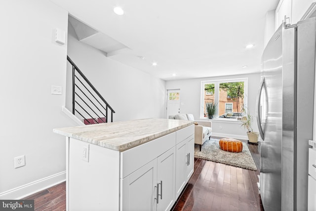 kitchen featuring dark hardwood / wood-style flooring, a kitchen island, white cabinets, and stainless steel refrigerator