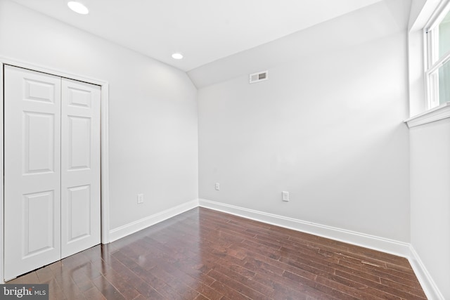 unfurnished bedroom with vaulted ceiling, dark hardwood / wood-style floors, and a closet