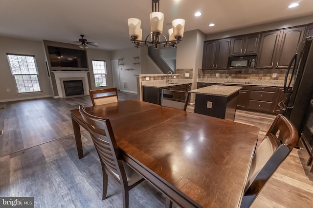 dining area featuring ceiling fan with notable chandelier, sink, and light hardwood / wood-style floors