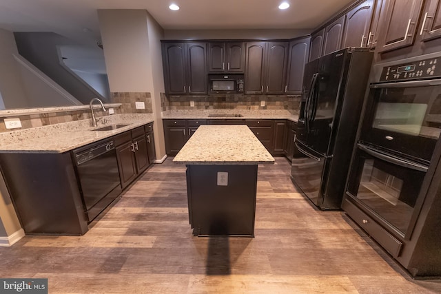 kitchen featuring dark brown cabinetry, sink, black appliances, and a center island