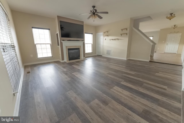 unfurnished living room with ceiling fan, a healthy amount of sunlight, and dark hardwood / wood-style floors