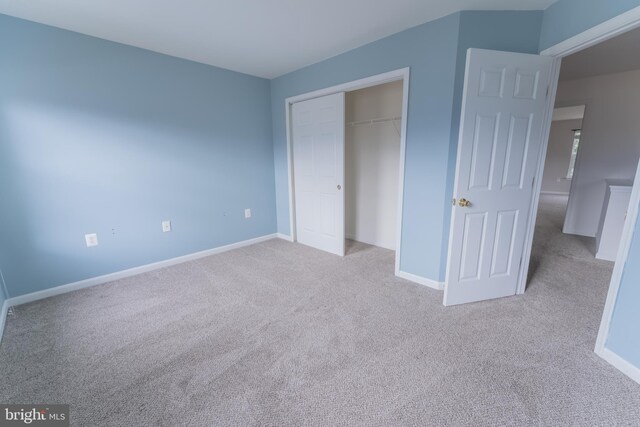 unfurnished bedroom with light carpet and a closet