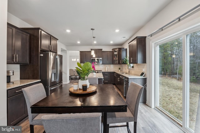 kitchen featuring sink, dark brown cabinets, appliances with stainless steel finishes, pendant lighting, and backsplash