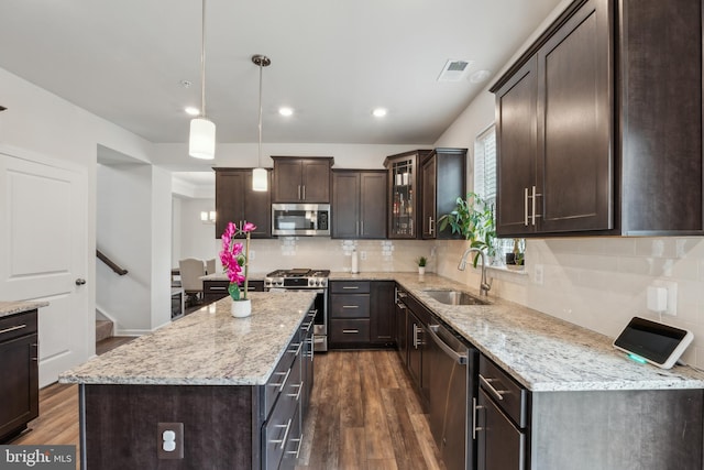 kitchen with sink, decorative light fixtures, dark brown cabinets, appliances with stainless steel finishes, and a kitchen island