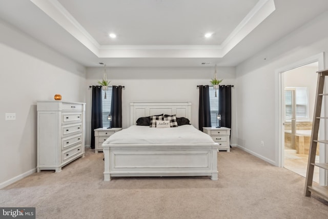 carpeted bedroom featuring crown molding, ensuite bath, and a raised ceiling