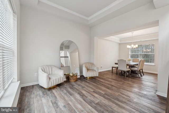 sitting room featuring wood-type flooring, ornamental molding, a raised ceiling, and a chandelier