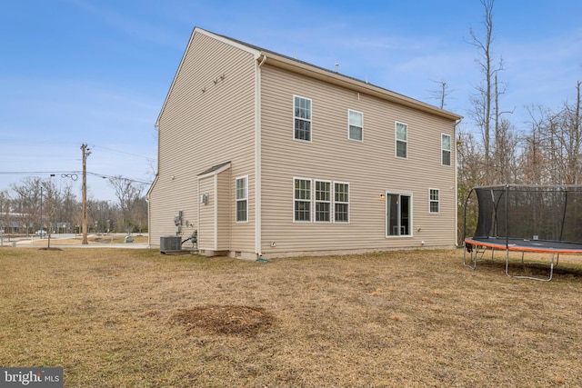 back of property featuring a yard, a trampoline, and central air condition unit