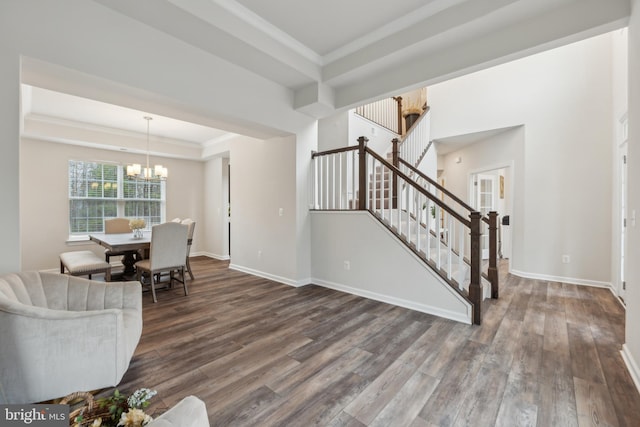 living room with crown molding, a tray ceiling, dark hardwood / wood-style floors, and a notable chandelier