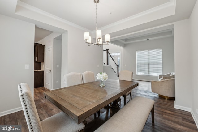 dining room featuring ornamental molding, dark hardwood / wood-style flooring, a raised ceiling, and a notable chandelier