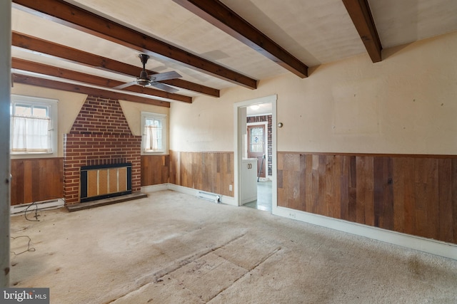 unfurnished living room featuring a fireplace, wood walls, a baseboard heating unit, ceiling fan, and beam ceiling