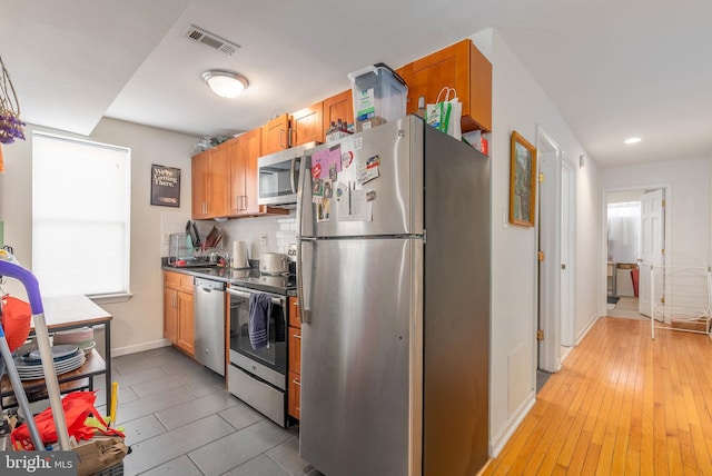 kitchen featuring appliances with stainless steel finishes, light hardwood / wood-style flooring, and decorative backsplash