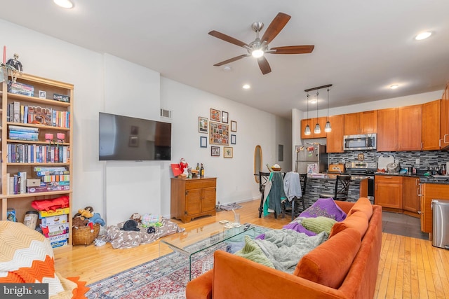 living room with ceiling fan and light wood-type flooring