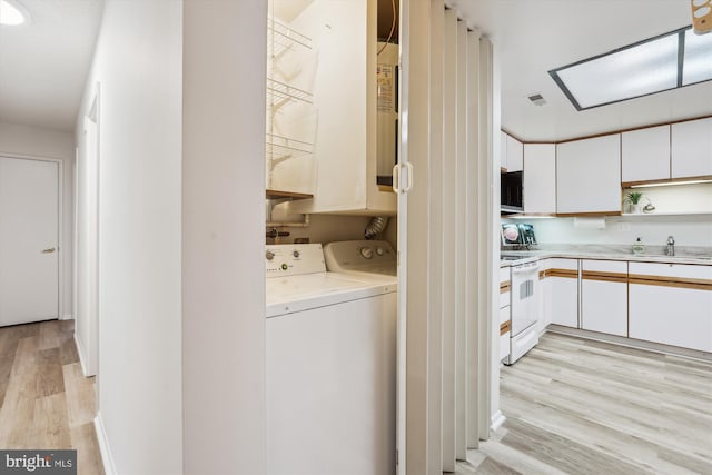 laundry area featuring laundry area, visible vents, independent washer and dryer, light wood-style floors, and a sink