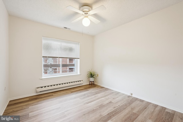 spare room with visible vents, a textured ceiling, a baseboard heating unit, and wood finished floors