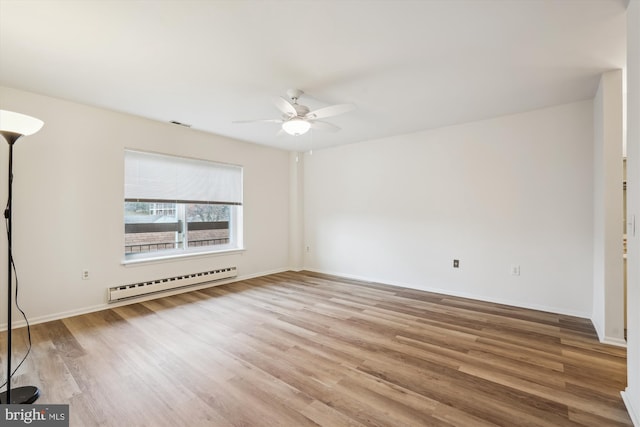 unfurnished room with ceiling fan, a baseboard heating unit, wood finished floors, visible vents, and baseboards