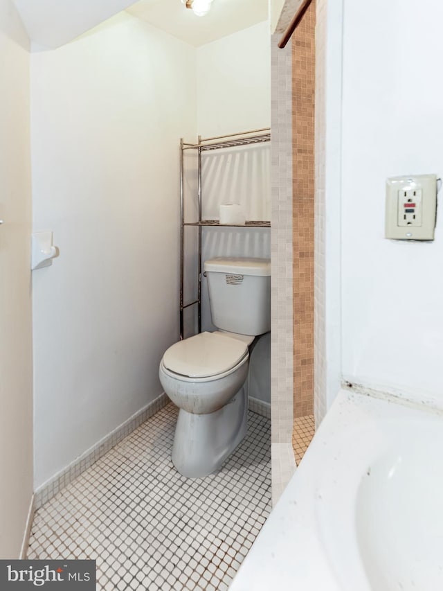 full bath featuring baseboards, tiled shower, toilet, and tile patterned floors