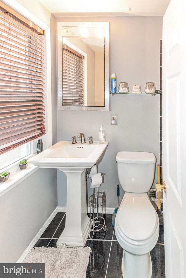 bathroom with baseboards, granite finish floor, and toilet